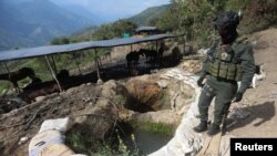 A policeman stands next to a well where minerals taken from illegal gold mines are washed in Buritica, Colombia, on April 20, 2021. (REUTERS/Luisa Gonzalez)