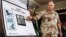 U.S. Army General Norman Schwarzkopf points to row of photos of Kuwait's Ahmadi Sea Island Terminal on fire after a U.S. attack on the facility, January 27, 1991. 