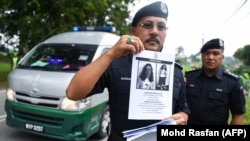 Seorang petugas dari Polis Diraja Malaysia menunjukkan poster bergambar Nora Quoirin, remaja Perancis-Irlandia berusia 15 tahun yang hilang di Seremban, Malaysia, pada Agustus 2019. (Foto: Mohd Rasfan/AFP)