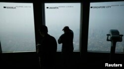 A woman looks at central Seoul shrouded in heavy haze at an observation platform at "N Seoul Tower" located atop Mt. Namsan in central Seoul, Feb. 27, 2014.