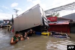 Orang-orang berjalan di jalan yang banjir akibat Badai Tropis Trami di Naga, Camarines Sur pada 25 Oktober 2024. (Foto: AFP)