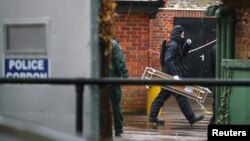 Police officers in black protective suits arrive with new equipment in the cordoned off area around The Mill public house, which had been visited by Sergei Skripal, in Salisbury, Britain, April 4, 2018. REUTERS/Hannah McKay 