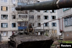 An Ukrainian serviceman sits atop an infantry fighting vehicle, near the bombed-out eastern city of Bakhmut