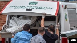 Policías descargan los cadáveres de víctimas de una masacre presuntamente a manos de grupos armados en el municipio colombiano de Arauca, en la morgue de Arauca, cerca de la frontera con Venezuela, el 22 de agosto de 2020.