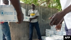 FILE - Men form a chain gang to distribute boxes of food aid, on March 14 2019, in the Mutoko rural area of Zimbabwe to help fight drought-induced hunger.