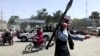 视频截图显示，一名塔利班战斗人员跑向喀布尔机场外的人群。(2021年8月16日)