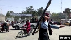 A Taliban fighter runs towards a crowd outside Kabul airport, Kabul, Afghanistan, Aug. 16, 2021, in this still image taken from a video. 