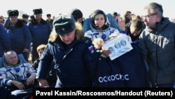 Ground personnel carry the International Space Station (ISS) crew member Russian actor Yulia Peresild after landing in a remote area outside Zhezkazgan, Kazakhstan, Oct. 17, 2021.