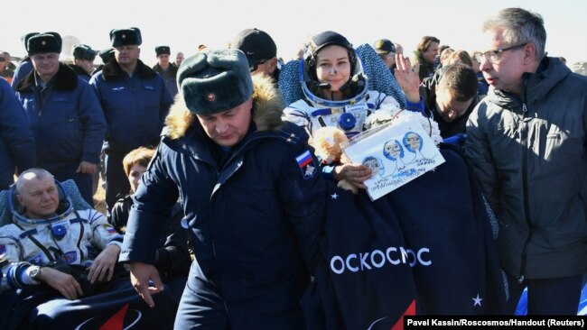 Ground personnel carry the International Space Station (ISS) crew member Russian actor Yulia Peresild after landing in a remote area outside Zhezkazgan, Kazakhstan, Oct. 17, 2021.