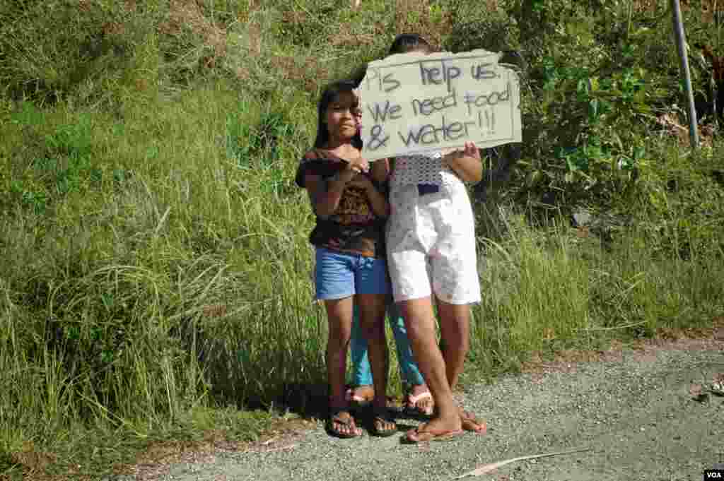 Children wait on roadsides to get handouts from passing motorists, Cebu, Philippines, Nov. 15, 2013. (Steve Herman/VOA)