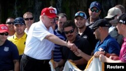 FILE - U.S. President Donald Trump gives out a commemorative "challenge coin" as he plays host to members of the U.S. Coast Guard he invited to play golf at his Trump International Golf Club in West Palm Beach, Fla., Dec. 29, 2017. Administration officials are downplaying any significance of a U.S.-North Korea coin, 250 of which were recently minted.
