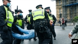 Police detain a man during a coronavirus anti-lockdown protest on Westminster Bridge in London, Oct. 24, 2020. 
