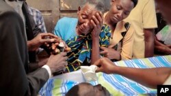 Relatives mourn over the body of Theogene Niyondiko, shot dead Friday by police during a protest against a third term for President Pierre Nkurunziza, in Bujumbura, Burundi, June 9, 2015.