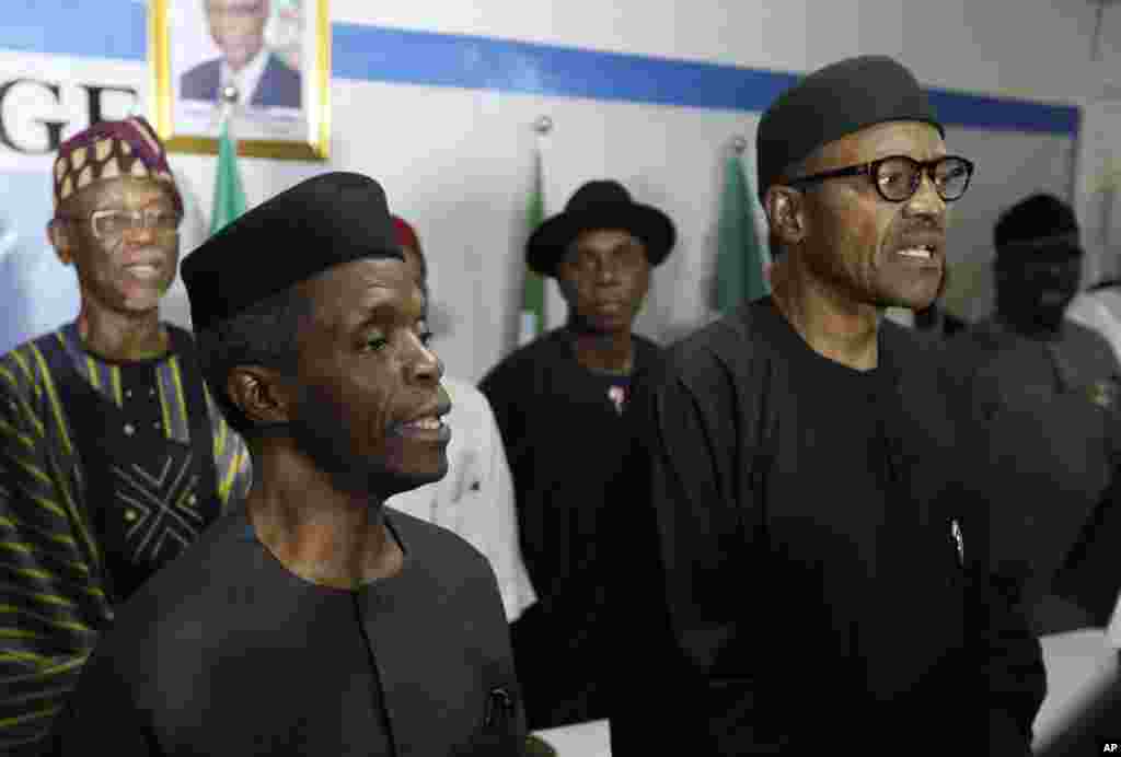Newly-elected Nigerian president Muhammadu Buhari (right) and his deputy, Yemi Osibnajo, sing the national anthem after speaking to journalists in Abuja, April 1, 2015.