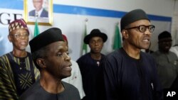 Nigerian former Gen. Muhammadu Buhari, right, along with his deputy, Yemi Osibnajo, sings the national anthem after speaking to journalists in Abuja, Nigeria, April 1, 2015. 