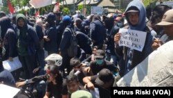 Seorang mahasiswa membawa kertas bertuliskan dukungan pengesahan RUU P-KS pada aksi di depan gedung DPRD Jawa Timur (foto Petrus Riski-VOA).