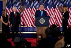 President Donald Trump speaks in the East Room of the White House, Nov. 4, 2020, in Washington, as Vice President Mike Pence and his wife Karen and First Lady Melania Trump listen.