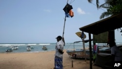 In this Friday, May 10, 2019, photo, a Sri Lankan reef safari boat operator stands on an empty beach in Hikkaduwa, Sri Lanka. (AP Photo/Eranga Jayawardena)