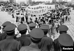 FILE - Chinese police monitor a march by tens of thousands of pro-democracy protesters in the special economic zone of Shenzhen in southern China on May 22, 1989.
