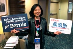 Una Lee Jost, a lawyer from Pasadena, Californi, holds signs supporting Bernie Sanders at the California Democratic Convention in Long Beach, California, Nov. 16, 2019.