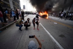 An Atlanta Police Department vehicle burns as people pose for a photo during a demonstration against police violence, Friday, May 29, 2020, in Atlanta.