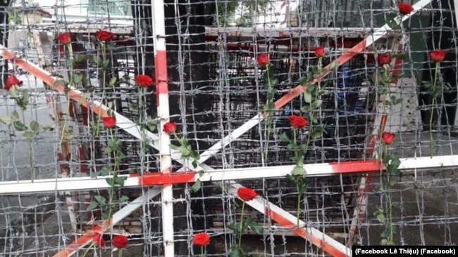 Người dân cài hoa hồng lên hàng rào kẽm gai trước đó được dùng để quây khu vực "trại giam" của công an ở Công viên Tao Đàn, quận 1 TP HCM. (Facebook Lê Thiệu)