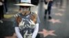FILE - A woman wearing an outfit with the names of men in Hollywood she claims sexually harassed her, is seen during a protest march for survivors of sexual assault and their supporters, in Hollywood, Los Angeles, California, Nov. 12, 2017.