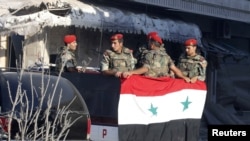 Soldiers loyal to the Syrian regime stand in a truck in Qusair after the Syrian army took control of the city from rebel fighters, June 5, 2013.