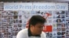 FILE - A Thai journalist walks past a banner before the International World Press Freedom Day a press conference in Bangkok, Thailand, May 3, 2017. 