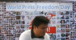 FILE - A Thai journalist walks past a banner before the International World Press Freedom Day a press conference in Bangkok, Thailand, May 3, 2017.