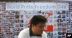 FILE - A Thai journalist walks past a banner before the International World Press Freedom Day a press conference in Bangkok, Thailand, May 3, 2017.