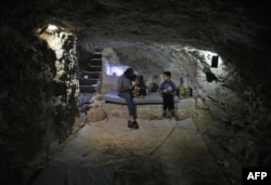A man sits with his children in a cave that he dug inside his house to shelter him and his family as part of preparations for any upcoming raids in the rebel-held Idlib province's village of Maar Shurin, Sept. 11, 2018.