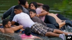 ARCHIVO - Un grupo de migrantes atravesaba a mediados de 2023 en una balsa inflable y sobrecargada desde México a Estados Unidos a través del Río Bravo, el paso se considera una cruce peligroso para los migrantes irregulares por las corrientes del afluente.