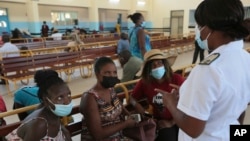 A nurse speaks to people waiting to be vaccinated with a COVID-19 vaccine at a public hospital in Harare, Zimbabwe, Dec. 1, 2021. 