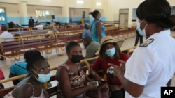 A nurse speaks to people waiting to be vaccinated with a COVID-19 vaccine at a public hospital in Harare, Zimbabwe, Dec. 1, 2021. 