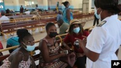 A nurse speaks to people waiting to be vaccinated with a COVID-19 vaccine at a public hospital in Harare, Zimbabwe, Dec. 1, 2021. 