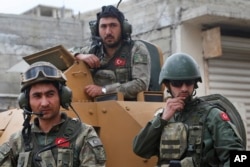 FILE - In this March 24, 2018 file photo, Turkish soldiers atop an armored personnel carrier secure the streets of the northwestern city of Afrin, Syria.