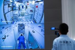 FILE - A worker monitors screens showing the interior of the Tianhe space station module after Chinese astronauts docked with and entered it, at the Beijing Aerospace Control Center in Beijing, June 17, 2021.