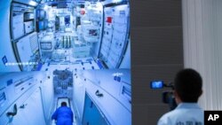 FILE - A worker monitors screens showing the interior of the Tianhe space station module after Chinese astronauts docked with and entered it at the Beijing Aerospace Control Center in Beijing, June 17, 2021. 