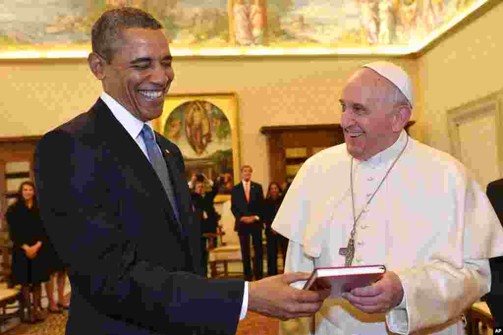 Pope Francis and U.S. President Barack Obama smile as they exchange gifts, at the Vatican.