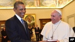 Pope Francis and President Barack Obama smile as they exchange gifts, at the Vatican, March 27, 2014.