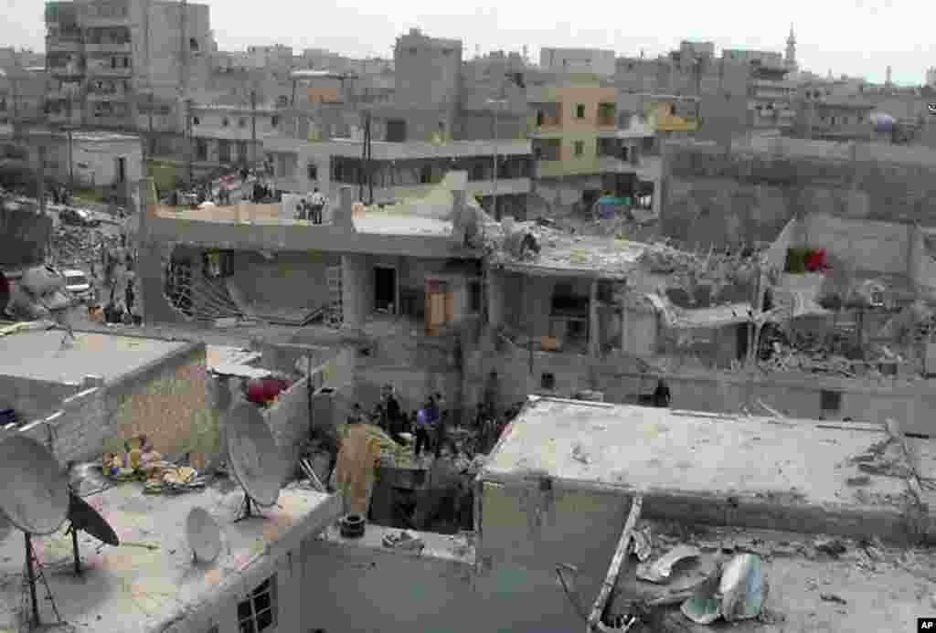 This citizen journalism image provided by AMC shows people on the top of houses that were damaged by an airstrike, Aleppo, Syria, April 15, 2013.