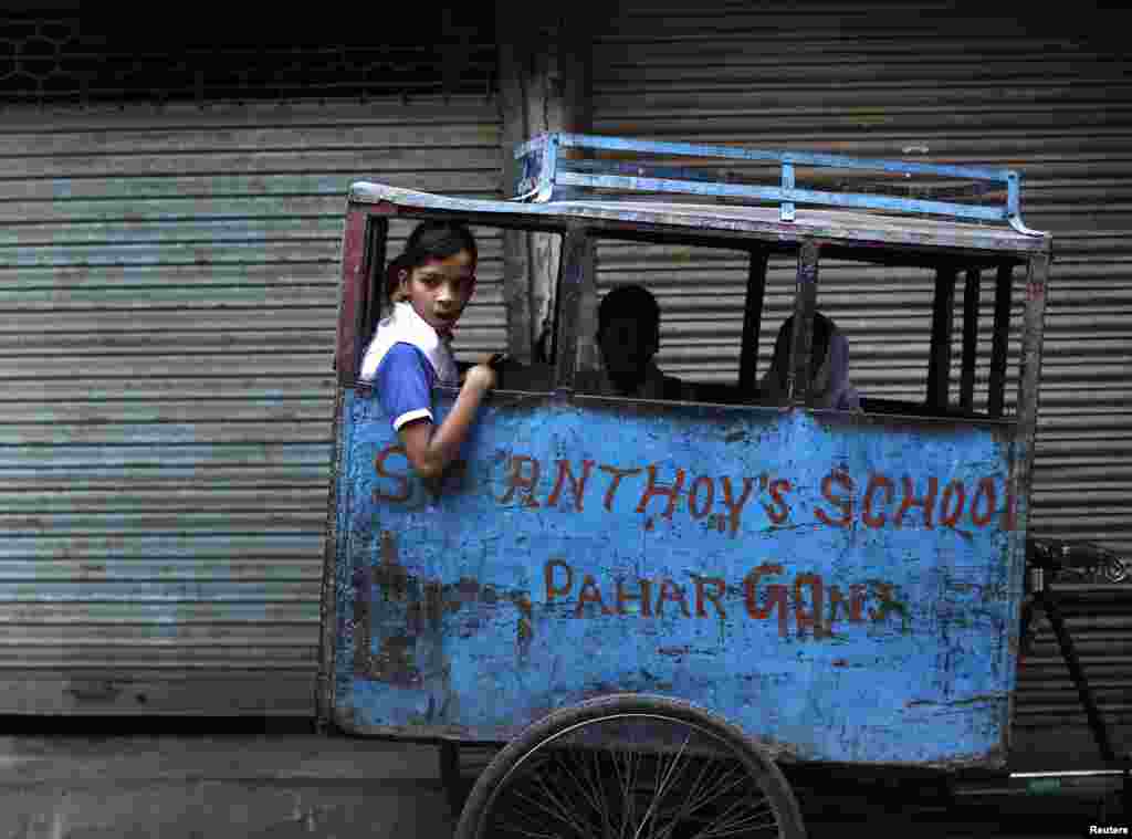 Schoolchildren wait for the rickshaw puller along the roadside in the morning at the old quarters of Delhi, India. 