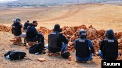 摄影师和记者坐在叙土边境的一座山丘上观看科巴尼的战斗。（2014年10月15日）