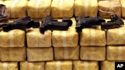 FILE - Guns are displayed on packs of confiscated methamphetamine during a news conference at police headquarters in Bangkok, Thailand, May 21, 2013. Police confiscated nearly 4.5 millions pills of methamphetamine as part of the raid.