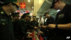 Vietnamese officers look at navy merchandise for sale aboard the aircraft carrier USS Carl Vinson during a carrier tour as it docks in Danang bay, Vietnam on Monday, March 5, 2018. (AP Photo/ Hau Dinh)