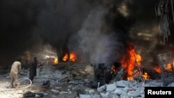 Men try to put out a fire at a market hit by air strikes in Idlib city, Syria June 12, 2016. 