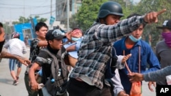 A man with a head injury is carried by fellow demonstrators during an anti-coup protest in Mandalay, Myanmar, March 22, 2021.