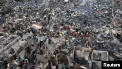 Warga berusaha mencari barang-barang yang masih bisa dipakai pasca kebakaran di kawasan kumuh Dhaka, Bangladesh (17/8). 