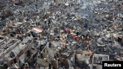 Slum dwellers search for their belongings from ashes after fire broke out on their shelters in Dhaka, Bangladesh, Aug. 17, 2019.